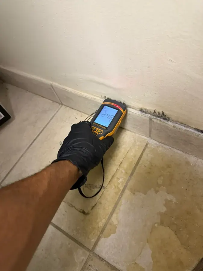 Pin meter checking moisture in a wet baseboard during a Duluth water damage inspection