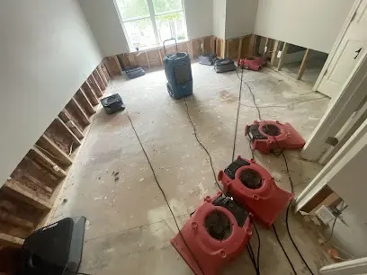 Air movers and a dehumidifier drying a room with flood cuts in Duluth